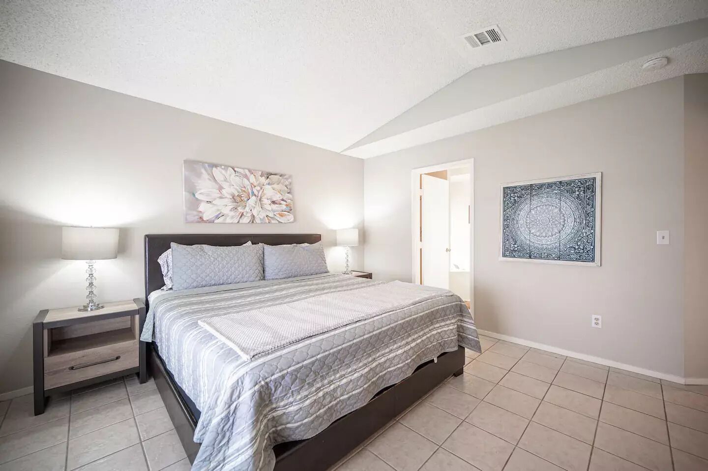 A bedroom with a bed, nightstands, and wall art.