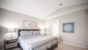 Een slaapkamer met een bed, nachtkastjes en wanddecoratie.