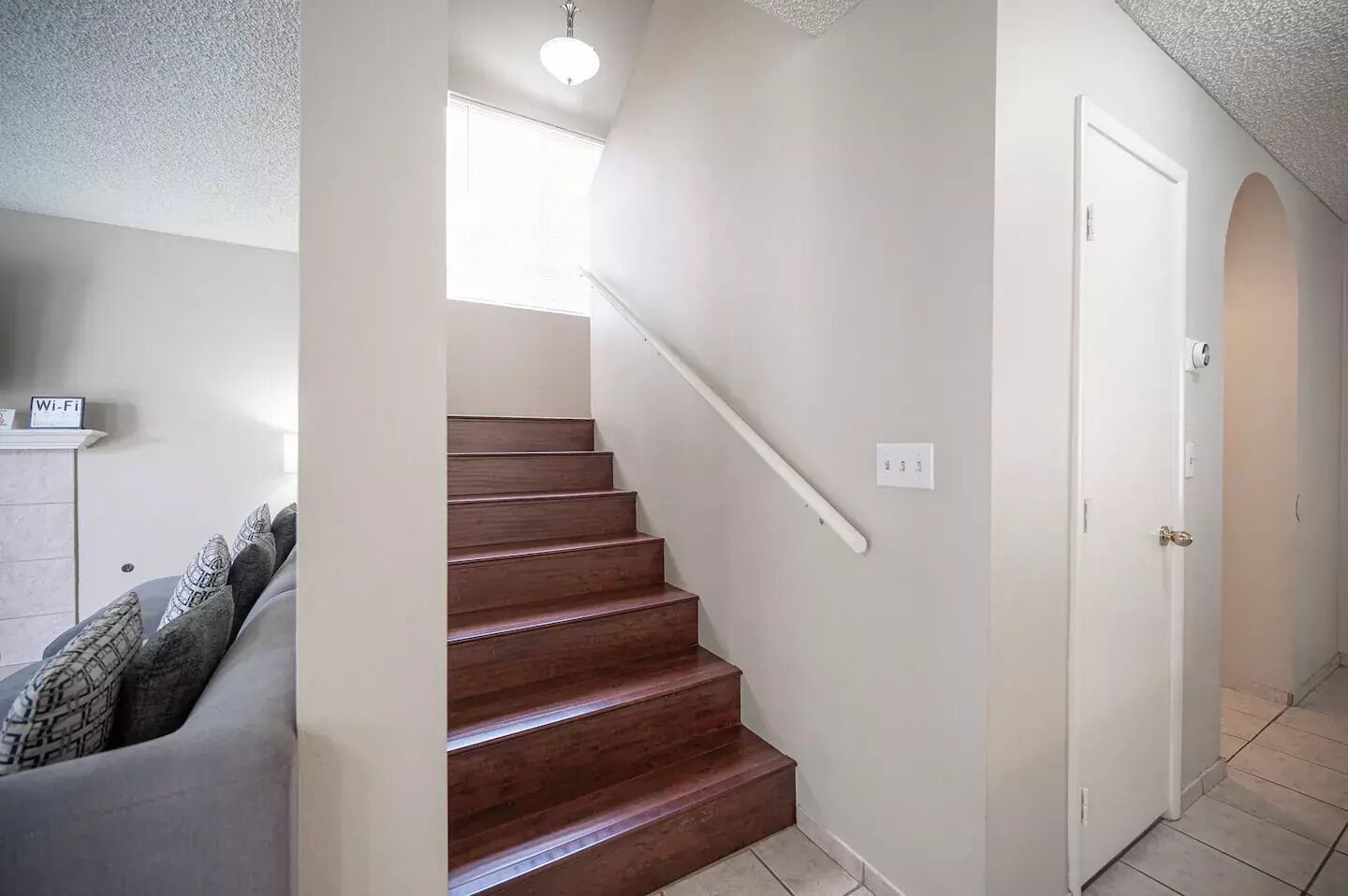 Eine Treppe mit Handlauf, eine weiße Tür und eine Deckenleuchte.