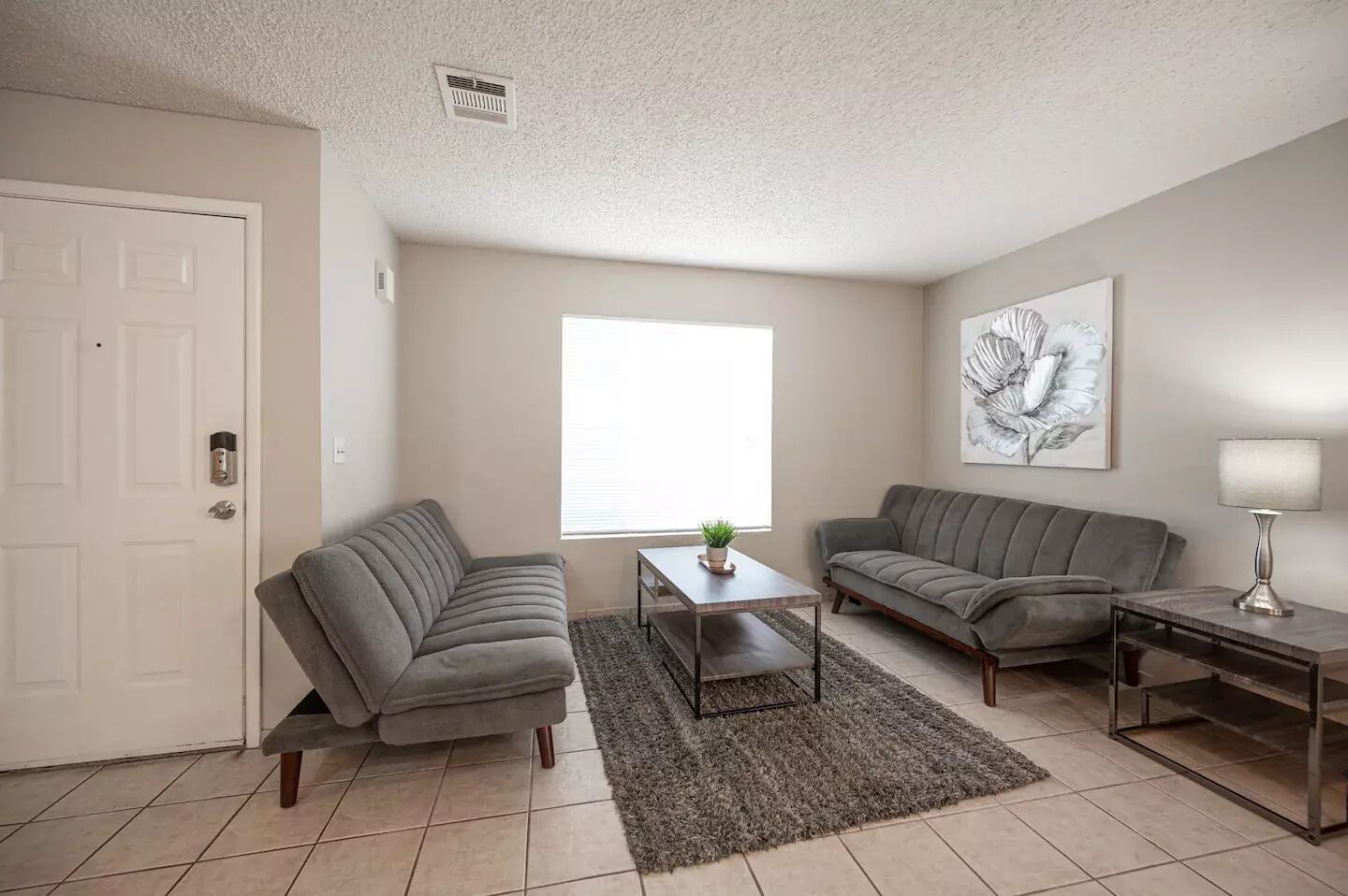 A living room with two grey sofas, a coffee table, a lamp, and a painting on the wall.