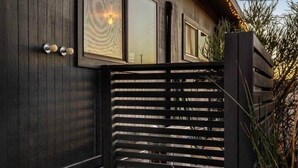 En modern byggnad med mörkt träpanel på fasaden, en svart metallgrind och en stensatt gångväg som leder till entrén.