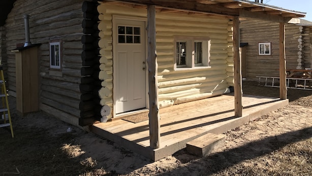 A log cabin with a front porch, a door, and a window. - Cabin #2 Near Beautiful Brevort Lake (Moran)