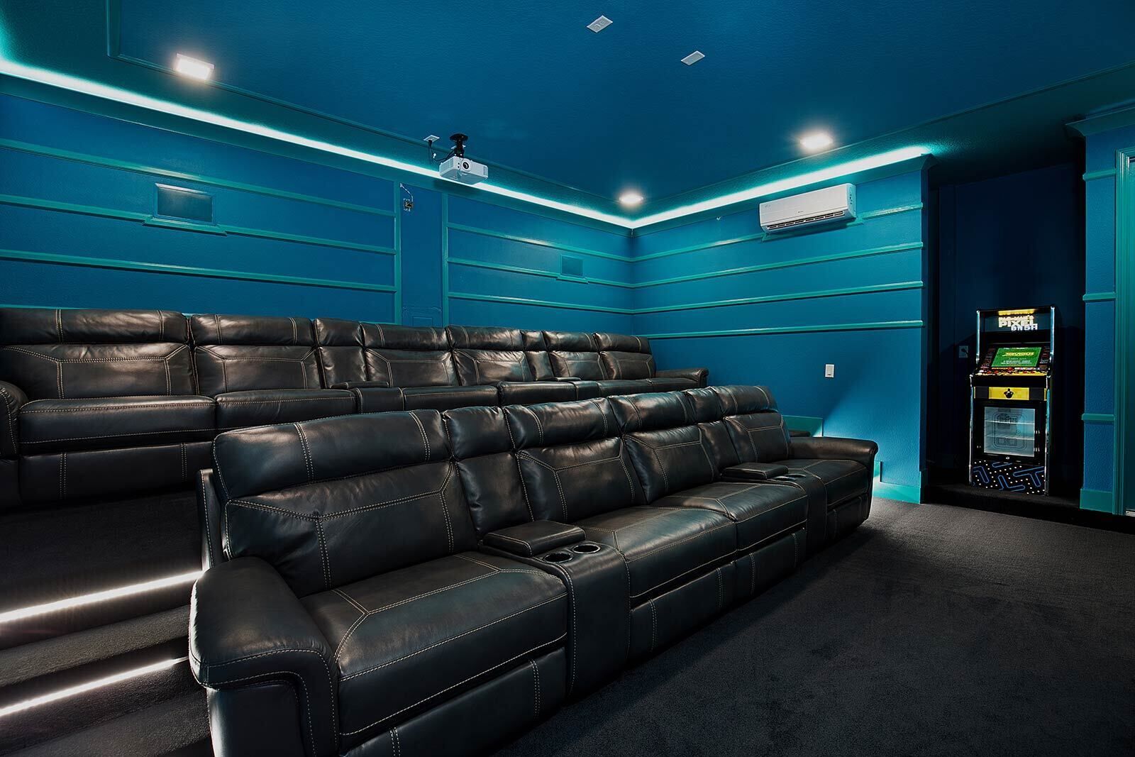 Ein Heimkinozimmer mit einer großen schwarzen Ledersofa und einer Spielkonsole.
