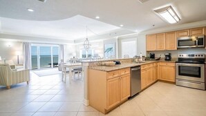 Een moderne keuken met een centraal eiland, inbouwapparatuur en een eetruimte met uitzicht.