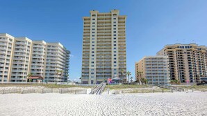 Een strandhotel met meerdere hoge gebouwen, een zandstrand en een trap naar het strand.