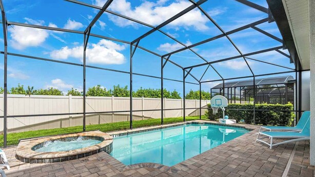 Una piscina al aire libre techada con un jacuzzi, una canasta de baloncesto y una tumbona.