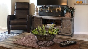 A living room with a leather chair, a flat-screen TV, a decorative trunk, and a plant on a wooden coffee table. - Palm Coast Fairway Vista (Palm Coast)
