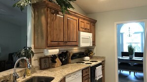 A kitchen with wooden cabinets, a white microwave, a stove, and a dishwasher. - Palm Coast Fairway Vista (Palm Coast)