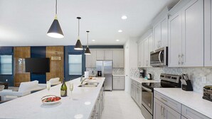 A modern kitchen with a large island, stainless steel appliances, and pendant lighting.