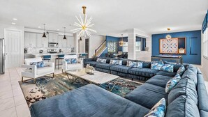 A modern living room with a sectional sofa, a dining area, and a kitchen.