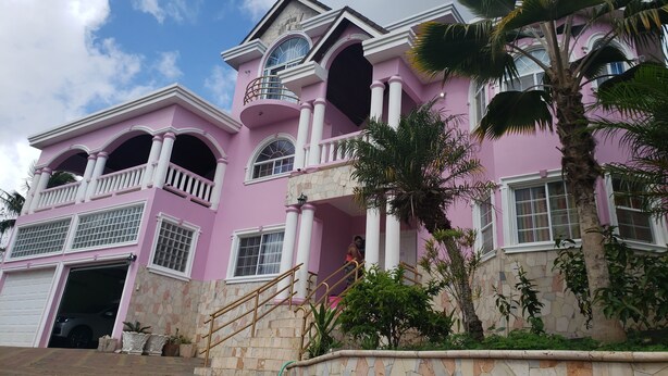 A pink building with a stone facade, large windows, and a staircase leading to a balcony. - DSH Vacation Rooms (Mandeville)