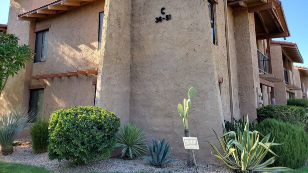 A building with a beige stucco exterior, a sign indicating 'Maximum Security', and a small cactus plant in the foreground. - PSP Dream Stay -  Large 2 bdm 2 bth condo- pickleball, tennis, all amenities  (Palm Springs)