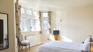 A bedroom with a large bed, a chair, a radiator, a television, and a window with curtains. - Luxury Apartment No.1, Whitefield (Whitefield)