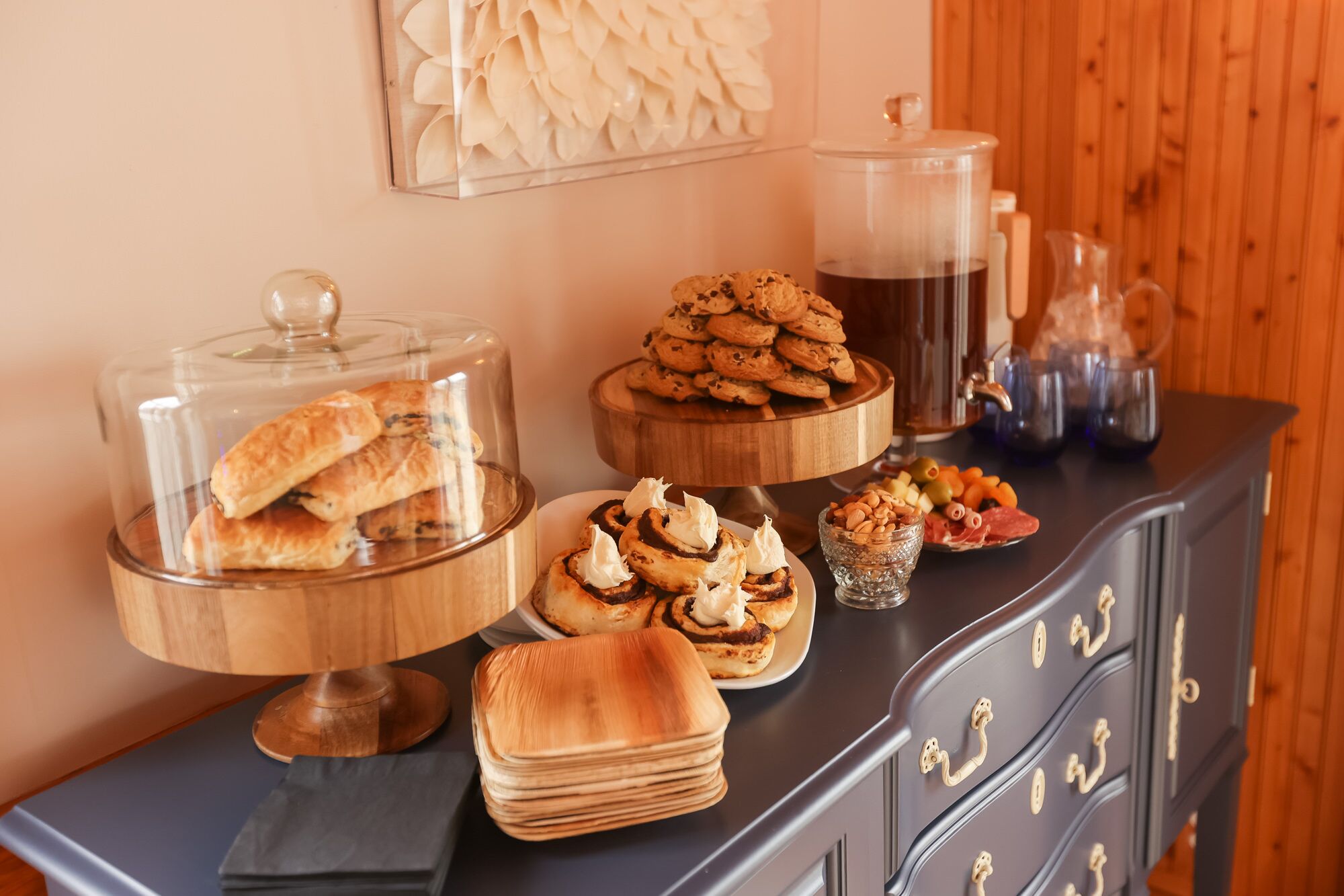A buffet table with various pastries, a coffee station, and a decorative wall piece.