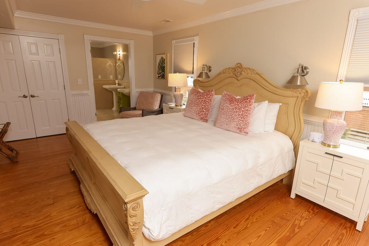 A bedroom with a large bed, a nightstand, a chair, and a wardrobe.