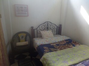 Simple, functional room with a single bed, chair, and framed picture.