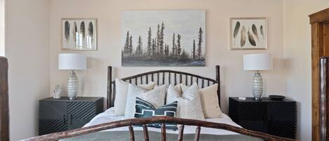 Une chambre à coucher avec un lit, deux tables de chevet et un tableau accroché au mur.