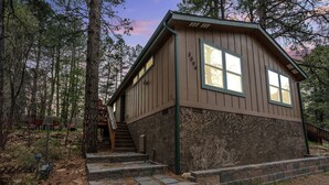 Una cabaña con fachada de madera, base de piedra y una escalera que conduce a la entrada.