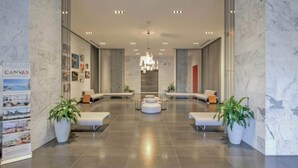 Eine großzügige Lobby im modernen Stil, mit einer zentralen Sitzecke, weißen Sofas und Topfpflanzen.