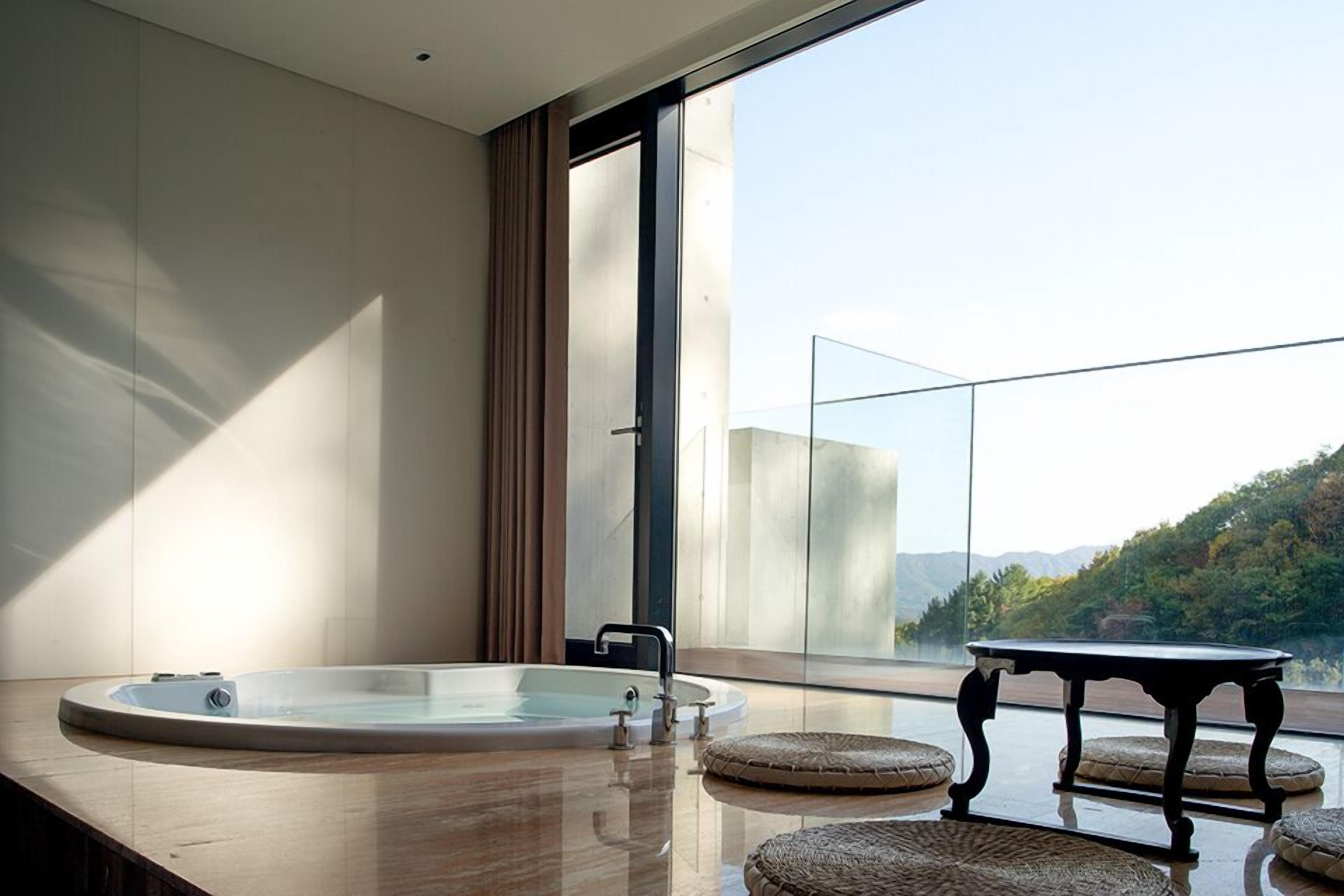 Un baño moderno con una bañera grande, cabina de ducha con paredes de vidrio y vistas a un paisaje montañoso.