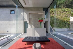 A modern outdoor seating area with a bench and a small table, surrounded by glass walls and a concrete structure. - Memory Maker (Gapyeong)
