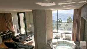 A modern living room with a sofa, a dining area, and a large window offering a mountain view.