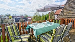 An outdoor dining area with a table set for four, surrounded by chairs, under a large umbrella.