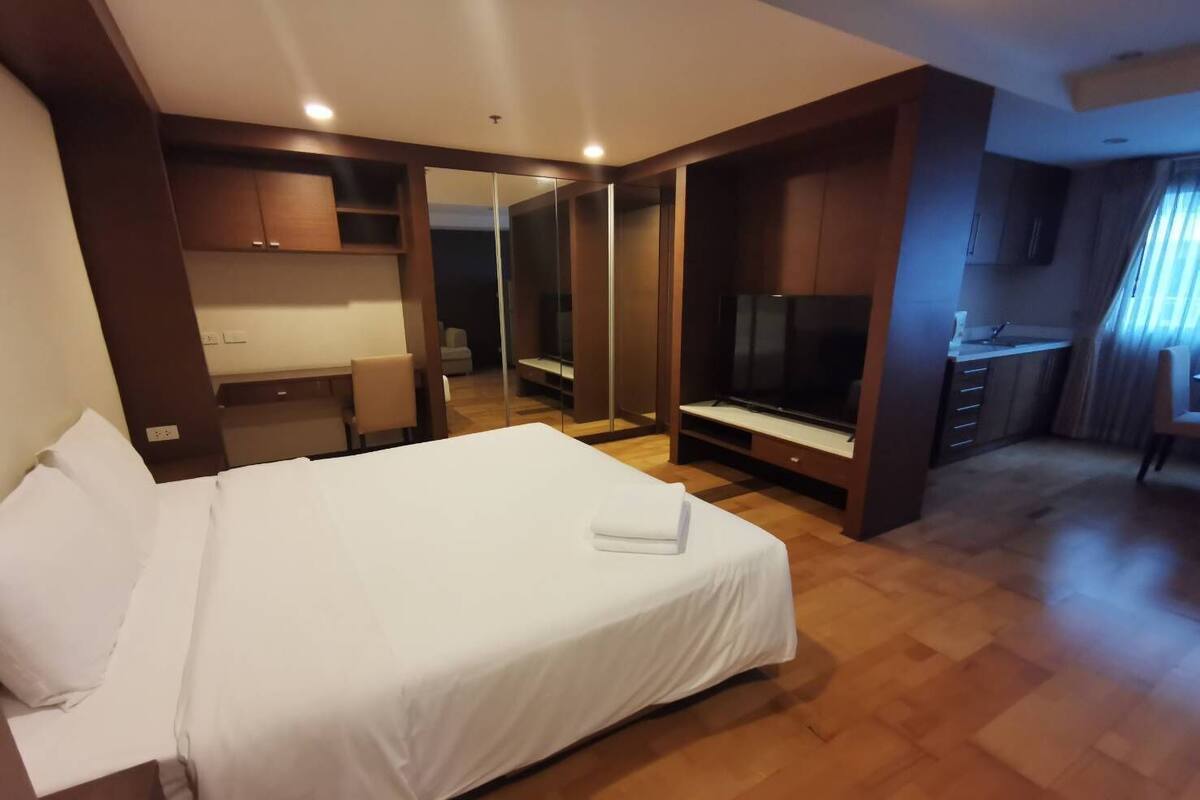 Hotellihuone, jossa on suuri sänky, televisio, työpöytä ja vaatekaappi.