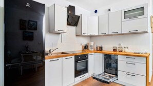 A modern kitchen with white cabinetry, a built-in oven, and a dishwasher.