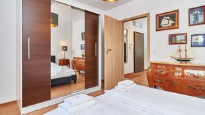 A hotel room with a bed, a wooden dresser, a mirror, and a wardrobe.