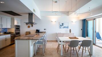 Una cucina moderna con isola centrale, elettrodomestici integrati e zona pranzo con tavolo e sedie.