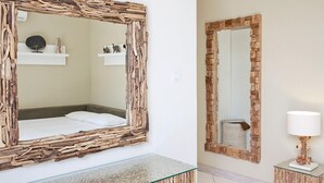 A bedroom with a rustic wooden-framed mirror, a bed, and a glass-top bedside table. - Le Chloe Villas (Seminyak)