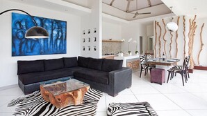A modern living room with a sectional sofa, a glass coffee table, and a zebra-patterned rug. - Le Chloe Villas (Seminyak)
