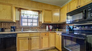 Keittiössä on puukaapit, astianpesukone, liesi ja mikroaaltouuni.
