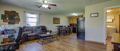 A spacious living area with a leather sofa, a coffee table, and a ceiling fan.