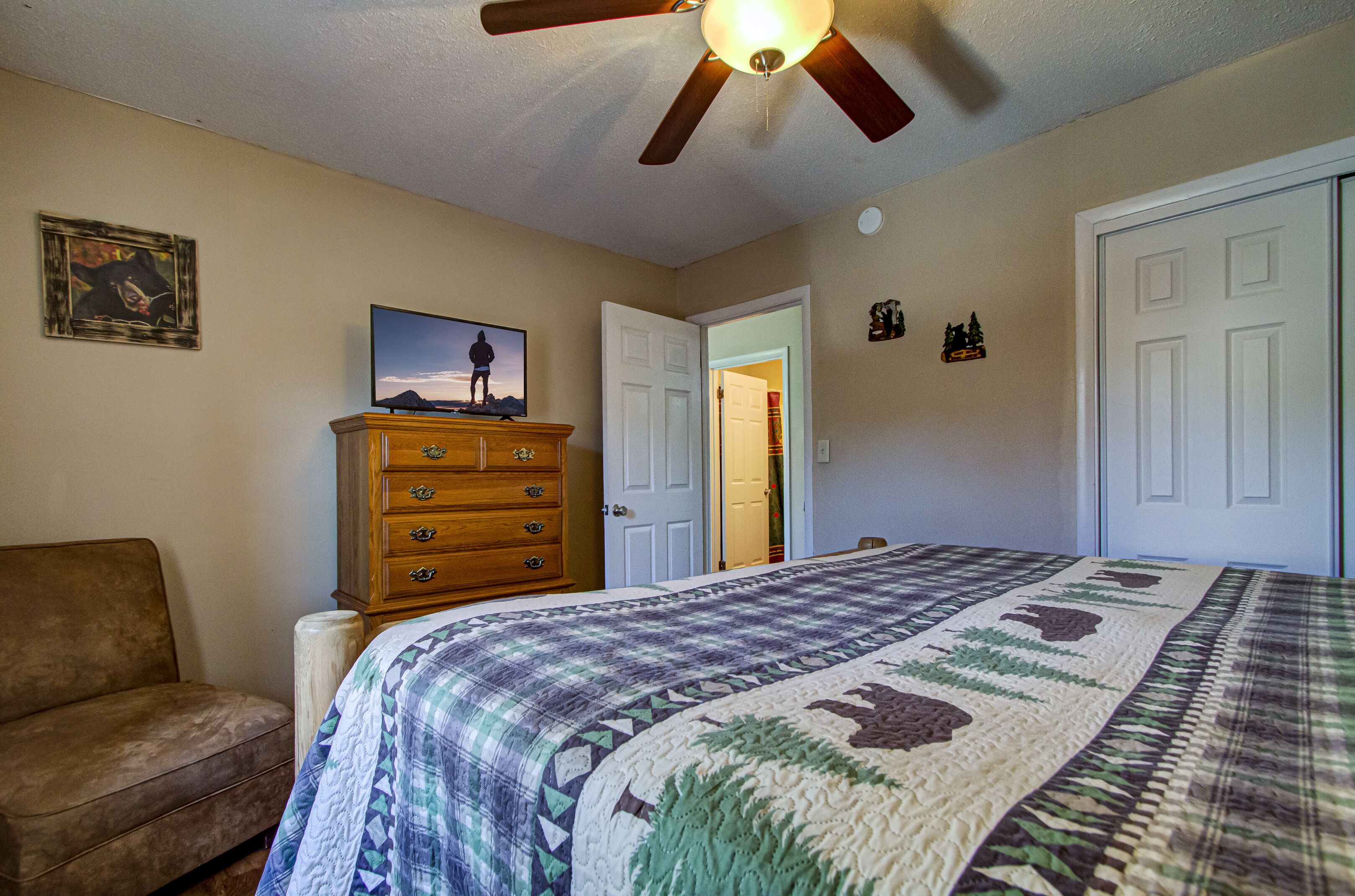 A bedroom with a bed, dresser, and a ceiling fan.