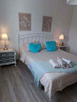 A neatly arranged bedroom with a bed, two nightstands, a lamp on each, a bedside table, and a wall-mounted lamp.
