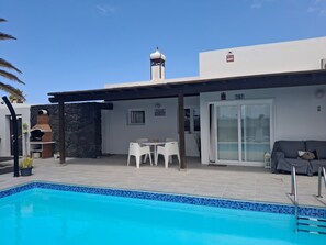 A poolside area with a barbecue, outdoor seating, and a covered patio. - Beautiful Villa "Mariola" Close to Beach with Heated Pool, Terrace, Garden & Wi-Fi (Playa blanca)