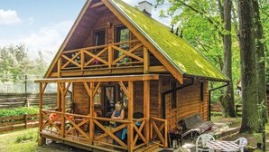 Una baita in legno con un balcone, un piccolo portico e una panchina.