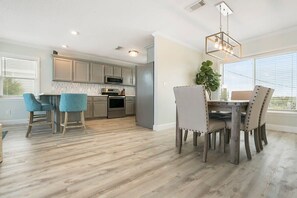 A modern kitchen with grey cabinets, stainless steel appliances, and a dining area with a wooden table and four chairs.