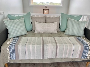 A bed with a striped blanket, multiple pillows, and a hanging light fixture above.