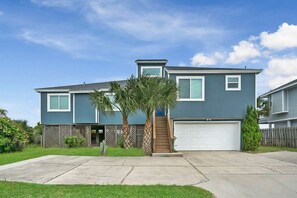 A two-story house with a garage, a front porch, and a small staircase leading to the entrance.