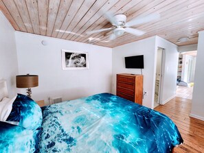 A bedroom with a bed, a ceiling fan, a TV, a dresser, and a framed picture on the wall. - Beach House with Ocean View, Heated Pool, and Rooftop Deck! Dog-friendly! (Cocoa Beach)