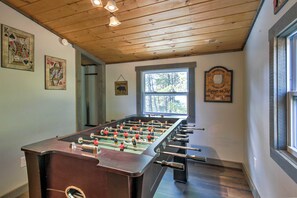 Une table de baby-foot dans une pièce avec un plafond en bois et une fenêtre.