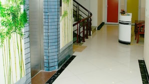 A hotel lobby with a modern design, featuring a staircase, a reception desk, and a wall with a bamboo mural. - Nam Son Hotel (Hanoi)