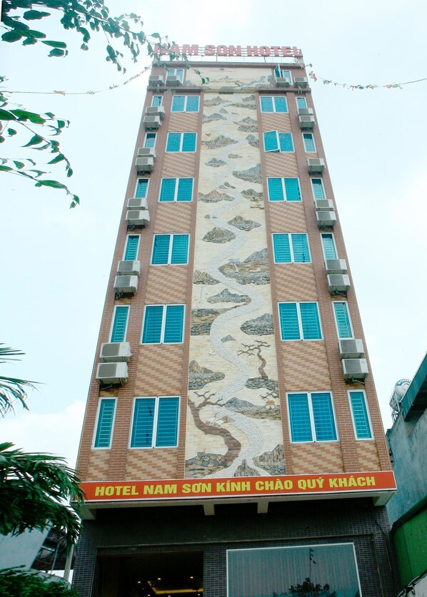 A hotel building with a prominent mural depicting a river flowing through a mountainous landscape. - Nam Son Hotel (Hanoi)
