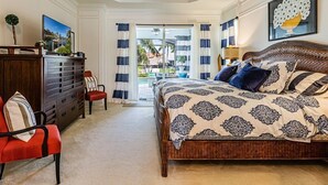 A bedroom with a large bed, a dresser, a chair, and a ceiling fan. - Marco's Charmer: luxury coastal living, magical sunsets, tranquil water views, relaxing hot tub. (Marco Island)