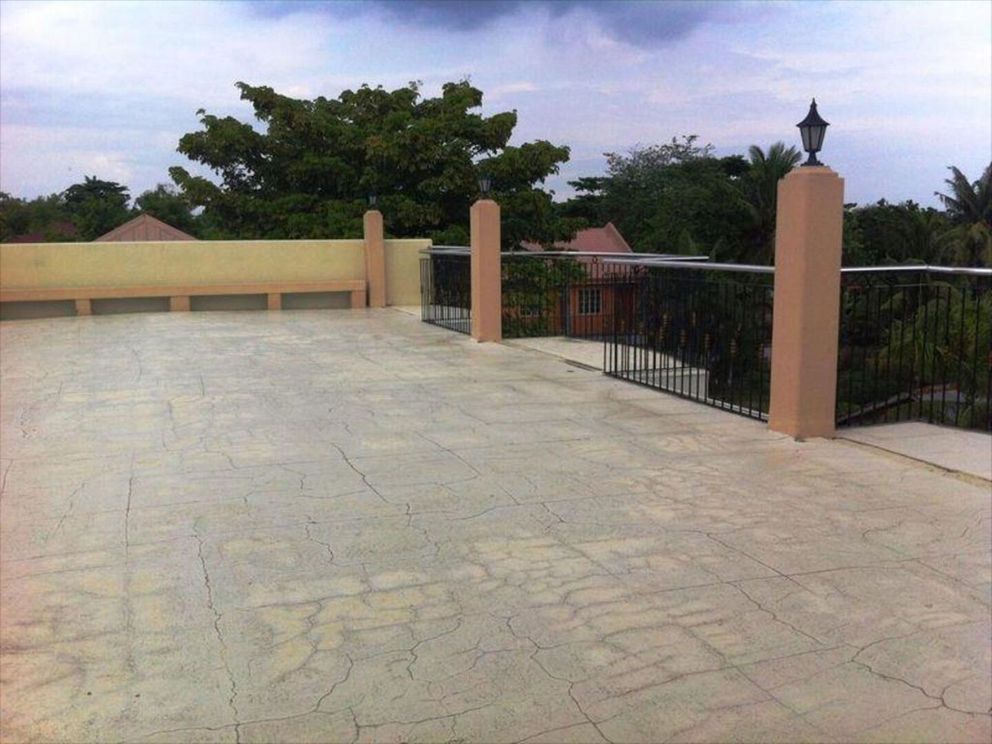 A rooftop terrace with a tiled floor, a metal railing, and a lamp post.