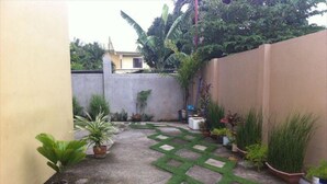 A small courtyard with a concrete path, potted plants, and a low wall. - Spurlock Residences (Lapu-Lapu)