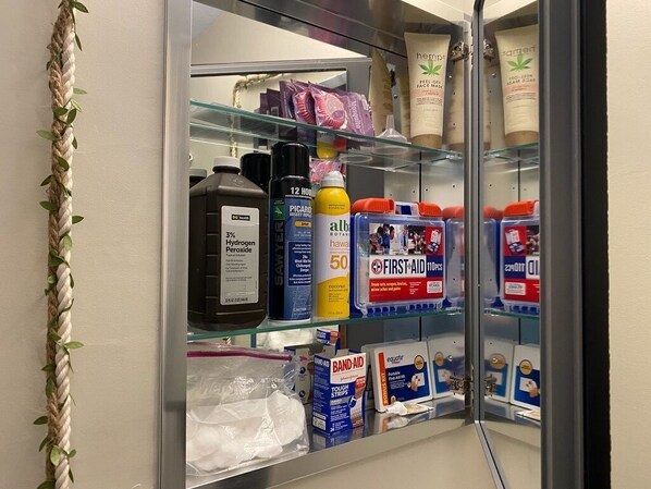 A bathroom with a glass shower enclosure, a towel rack, and various toiletries on shelves.
